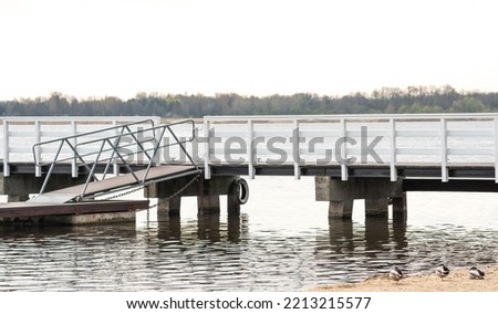 A white wooden pier over the water. Wooden structure on the beach by the lake.