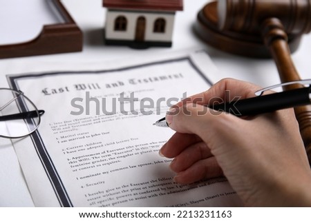 Woman signing last will and testament at white table, closeup Royalty-Free Stock Photo #2213231163