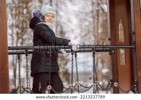 Little girl walks outdoors on winter snowy day in park. High quality photo