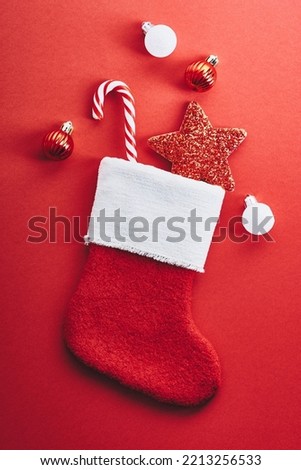 Christmas stocking with striped candy cane, star decoration, baubles on red background. Christmas Santa Claus socks. Winter holidays celebration concept.