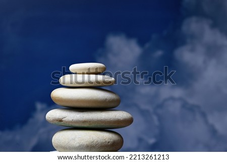 Pile of stacked stones with blue sky and clouds background