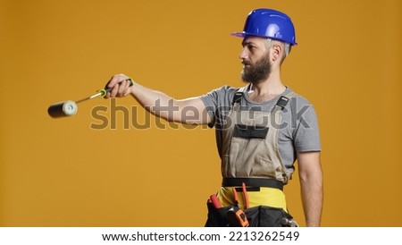 Portrait of industrial worker using paintbrush roller to paint walls with color, working on renovation project and rebuilding. Contractor with refurbishment tools doing rearrangement work.