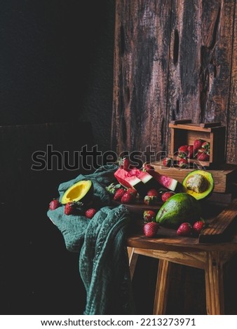 selective focus of watermelon in still life with avocado, strawberries and beautified with long green crumpled napkin in a blurry background