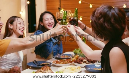 Group of happy young Asian people with friends celebrating clinking glasses during dinner party