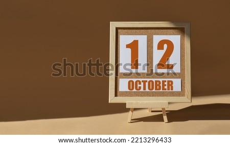 October 12th. Day 12 of month, Calendar date. Cork board, easel in sunlight on desktop. Close-up, brown background.  Autumn month, day of year concept.