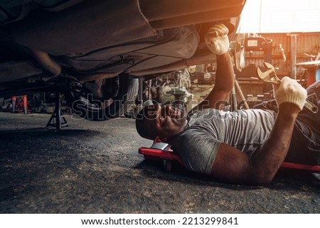 Auto mechanic are checking and repair maintenance underneath a car at the repair garage.	