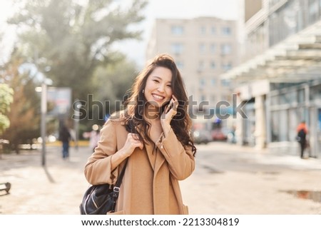 Lifestyle portrait happy Asian kazakh woman talking on mobile phone and laughing Royalty-Free Stock Photo #2213304819