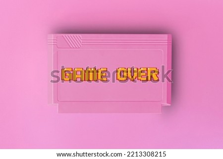 Pink 8 bit game cartridge  for retro game console on pink background. game over text . Minimal concept.