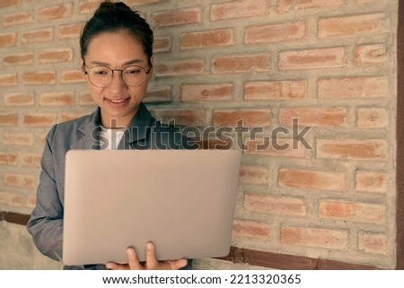 businesswoman standing holding a laptop enjoying applications with a happy smile.