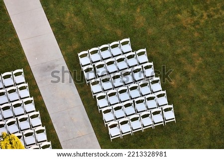 Top view of white resin folding chairs with padding aligned for wedding ceremony.