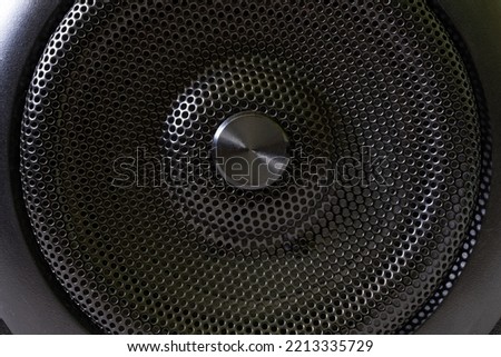 The central fragment of a modern audio speaker with a protective black metal grille. Macro. Close-up Royalty-Free Stock Photo #2213335729