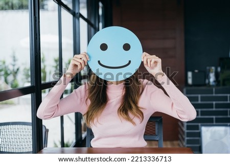 Asian woman holding blue happy smile face on paper cut, user giving good feedback rating, think positive , customer review, assessment, of mental health day, Compliment Day, satisfaction concept. Royalty-Free Stock Photo #2213336713