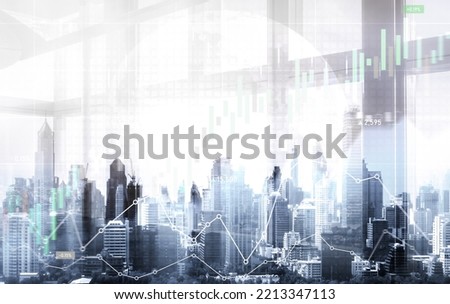 As background for a financial or business concept, digital screen and financial graphs overlap on a picture of modernistic cityscape, skyscrabbers.