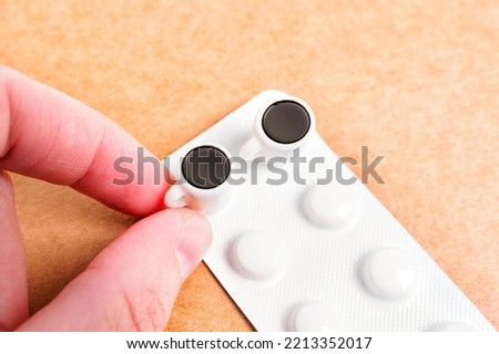 Hand takes a teeny-tiny coffee cup placed on a tablets blister isolated. Caffeine pills dosage concept. Royalty-Free Stock Photo #2213352017