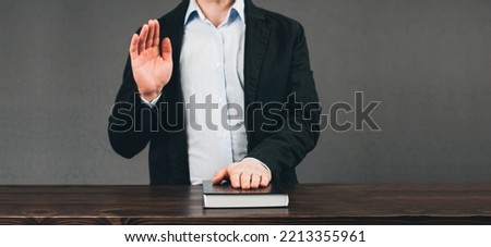 Oath. The promise of a man with his right hand raised. Sitting at the table Royalty-Free Stock Photo #2213355961
