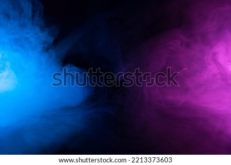 Clouds of smoke in blue and purple neon light swirling on black table background with reflection