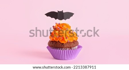 Tasty Halloween cupcake on pink background