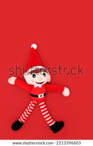Christmas elf toy santa helper tree decoration. Minimal festive design symbol on red background for winter, Xmas Eve and New Year season.