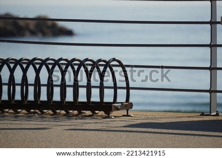 Close-up shot of a bicycle parking grid and a railing by the sea
