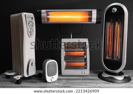 Modern electric infrared, oil and fan heater in living room Royalty-Free Stock Photo #2213426909