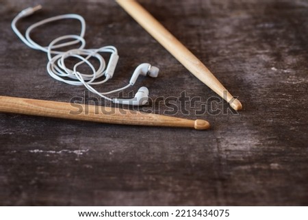 Drumsticks and earphones laid on a wooden desk background