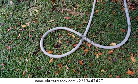 The water hose above the grassy field is used to water the garden and plants to keep them fresh.