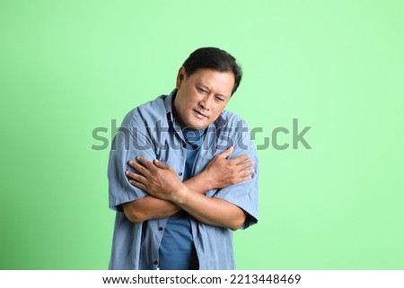 The 40s adult overweight Asian man standing on the green background.