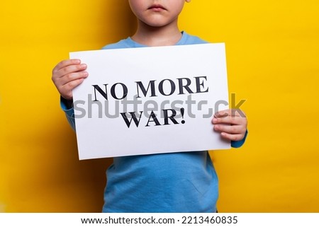 Peace. No more war. A child in a blue T shirt holds a poster with appeals for peace on a yellow background. no face, close up. war Russian and Ukrainians. High quality photo