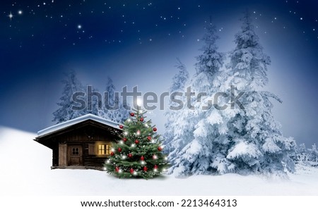 Shiny Christmas tree by a log cabin in the snow