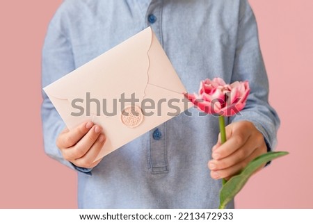 Closeup photography of child, holding in hands pink certificate gift with wax seal and tulip.Festive banner with copy space.