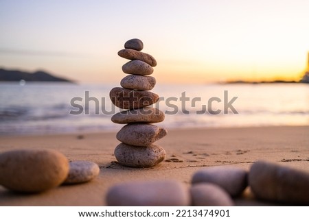 Balance pebble stone in the sand beach at sunset Royalty-Free Stock Photo #2213474901