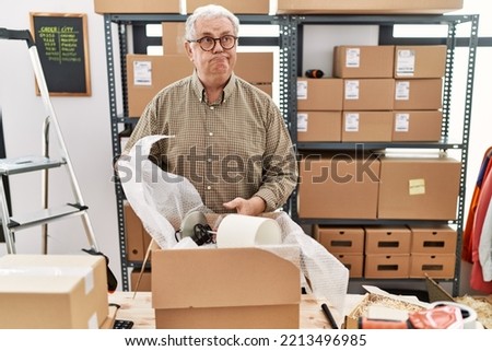 Senior caucasian man working at small business ecommerce packing order smiling looking to the side and staring away thinking. 