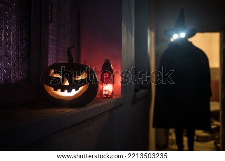 Halloween concept. Creepy silhouette in the dark corridor with pumpkin head. Toned light with fog on background. Selective focus. Long shutter shot