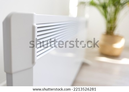 Modern electric heater on floor at home. Space for text. Modern electric convection heater on floor in stylish room interior.  Electric Heater in winter time. 