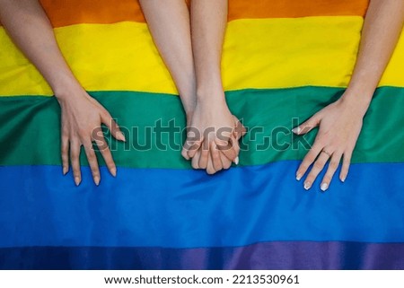 The women hands holding and a pride flag on the background