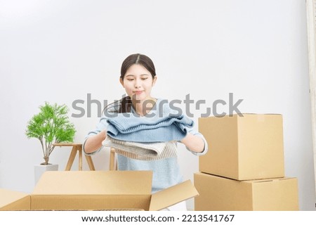 Asian woman putting a package in a cardboard box