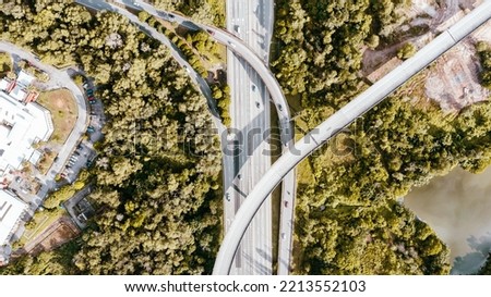 Aerial view directly above a six lane highway. Top view of asphalt road passes through the field and forest. Aerial. Sedan cars driving by the highway. Top view from drone. aerial photo autobahn road  Royalty-Free Stock Photo #2213552103