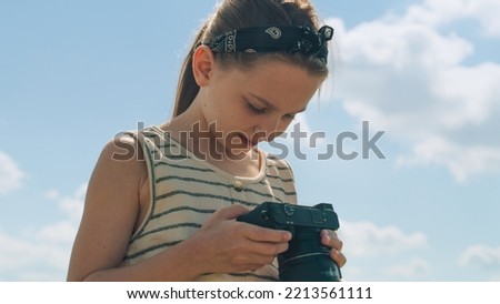 Young photographer shooting landscape. Girl taking pictures of nature, watching result, upgrading photography skills, spending leisure time outdoor. Close-up view.