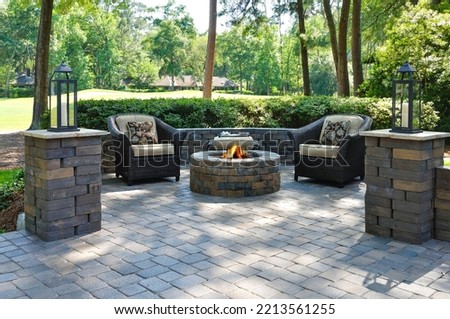 A beautiful outdoors pavers with two comfortable armchairs and a fire pit in a natural green environment Royalty-Free Stock Photo #2213561255