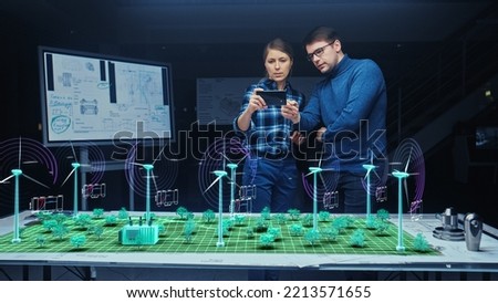 Renewable Energy Engineers Design 3D Wind Turbine Park Using Augmented Reality Software and Smartphone. Specialists Use Virtual Reality App to Work on Green Energy Power Production. Royalty-Free Stock Photo #2213571655