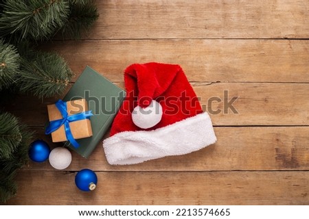 Santa Claus hat, gifts and branches of a Christmas tree on a wooden background. Top view, flat lay.