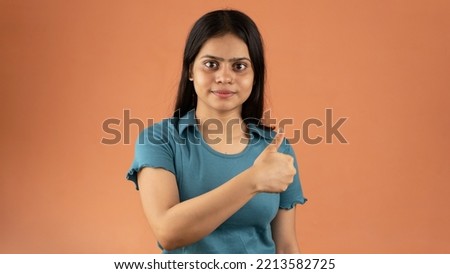 Young Indian woman isolated on color background smiling and raising thumb up