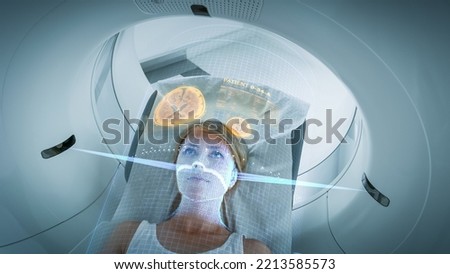 Female Patient Lying on a CT or PET or MRI Scan Bed, Moving Inside the Machine While it Scans Her Brain and Vital Parameters. AR Concept with Visual Effects In Medical Lab with High-Tech Equipment.