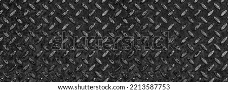 Tread plate, checker plate, diamond plate. Wide dark metal sheet with regular pattern for industrial background texture. Rusty black steel surface with copy space.