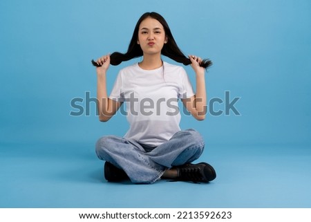 Beautiful girl sitting doing various poses On a blue background, sitting, smiling, happy, relaxing, excited, having fun.