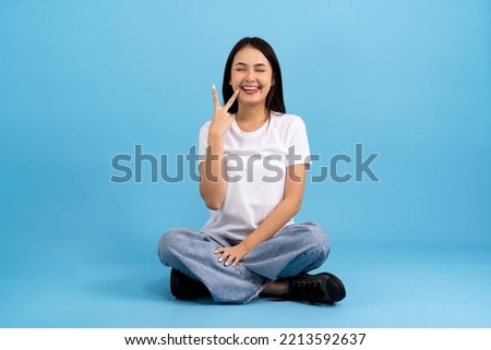 Beautiful girl sitting doing various poses On a blue background, sitting, smiling, happy, relaxing, excited, having fun.