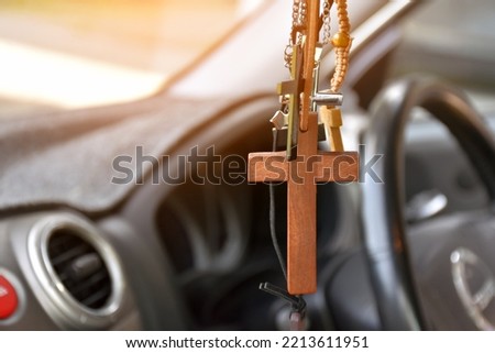Necklaces of various shapes of crosses are hung in the rearview mirror in the front console of the car as a talisman to prevent accidents while driving. Royalty-Free Stock Photo #2213611951