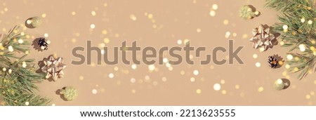 Winter banner made of  fir branches and christmas decoration on pastel beige background with golden lights. Christmas and new year concept. Flat lay. Top view, copy space.