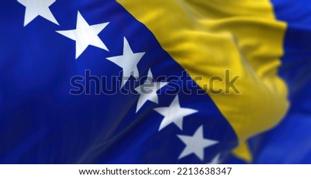 Close-up view of Bosnia and Herzegovina flag waving in the wind. Bosnia and Herzegovina is a country at the crossroads of south and southeast Europe. Fabric textured background. Selective focus Royalty-Free Stock Photo #2213638347
