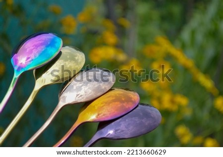 Multicolored table spoons on a plant green background, picture for an article about tableware or cutlery, with a copyspace